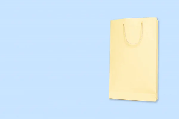 Ljusgul färg shopping Paper Bag på blå bakgrund med kopierings utrymme. — Stockfoto