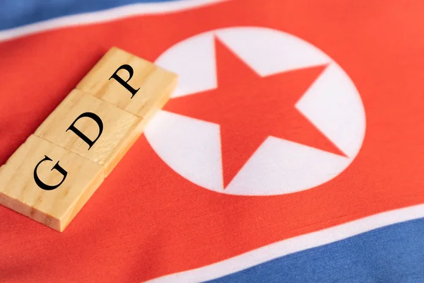 Produit intérieur brut ou PIB de la Corée du Nord en lettres moulées en bois sur le drapeau nord-coréen. — Photo