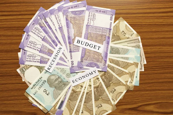 Budżet, gospodarka, recesja wydrukowany w papierze na indyjskiej curency jako tło na stole — Zdjęcie stockowe