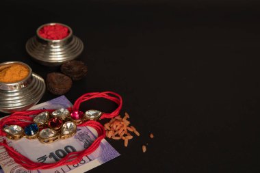 Raksha Bandhan oğuz veya Rakhi kumkum, Areca ve Hint currecny siyah arka planda.