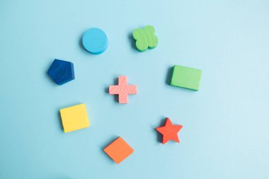 Top view Colorful Wooden building blocks with different shapes for developing and entertainment of Children on blue background. clipart