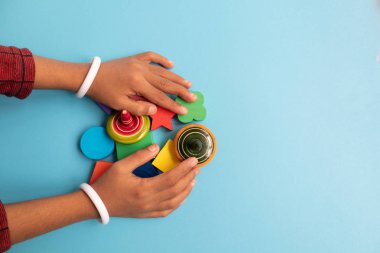 Top view of Hand of a Children grabbing colorful Wooden building blocks with different shapes for playing of Children on blue background. clipart