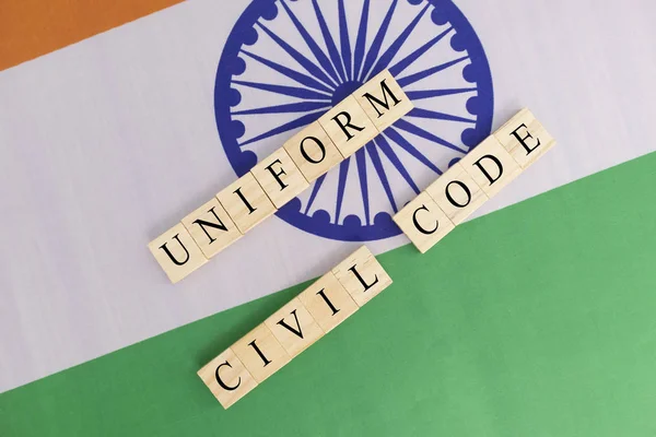 Concept of One law for all called Uniform Civil code or UCC in Indian constitution in wooden block letters on Indian flag.
