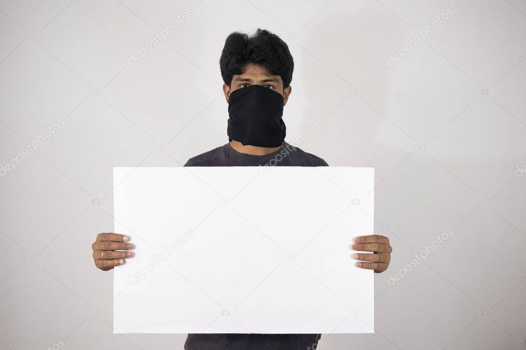 Concept of protest showing with Man standing by covering the face with black cloth and holding Empty banner, placarcd on isloated background.
