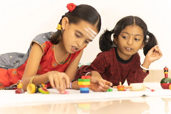 Interactivamente Dos niños indios o hermanas pequeñas jugando felizmente con juguetes de madera coloridos dentro del hogar . — Foto de Stock