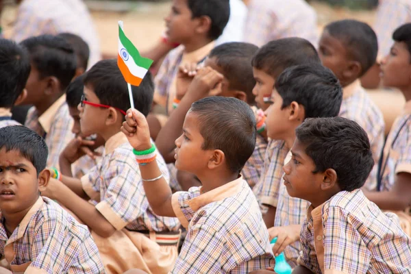 Група початкової школи діти сиділи на землі, утримуючи індійський прапор в руці в день незалежності Індії — стокове фото