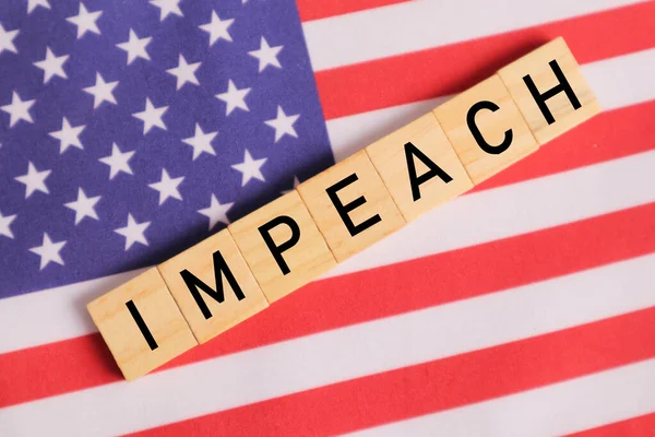 Concept of US politics, Impeachment showing with US flag with Impeach in wooden letters.