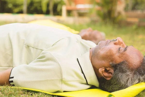 Hombres mayores practicando yoga - Shavasana o postura del cuerpo es el final de una clase o práctica - yoga para personas mayores, concepto activo y saludable de ancianos . — Foto de Stock