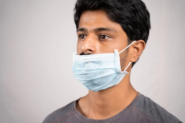 young man wearing medical mask below nose - concept showing of improper way of using face masks during coronavirus or covid-19 crisis