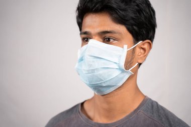 Genç adam yüz maskesi ile burun ve ağzı düzgün bir şekilde örttü - Koronavirüsten ya da izole bir arka plandaki Cvid-19 krizinden korunmak için maske takmak için farkındalık ve güvenlik kavramı.