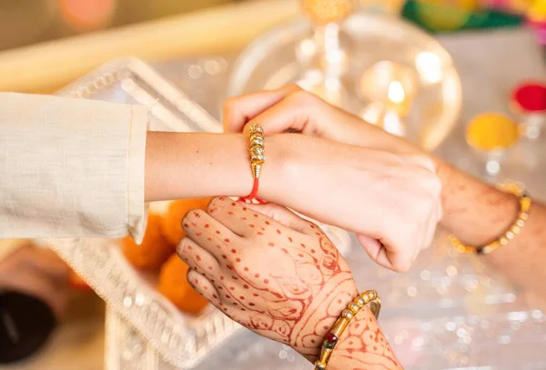 Close-up de mãos, irmã amarrando rakhi, Raksha bandhan para irmãos pulso durante o festival ou cerimônia - Rakshabandhan celebrado em toda a Índia como amor altruísta ou relacionamento entre irmão e irmã — Fotografia de Stock