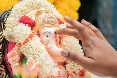 Hint dini Ganesha ya da Vinayaka Chaturthi festivali sırasında Tilak ya da Kumkum 'u Lord Ganesha' ya uygulayan ellerin yakınlaşması.
