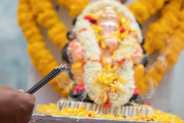 Ruce Držet nebo nabízí kadidlo nebo agarbatti hůl před lordem vinayaka nebo Ganesha při modlitbě nebo uctívání během slavnostního ceremoniálu — Stock fotografie