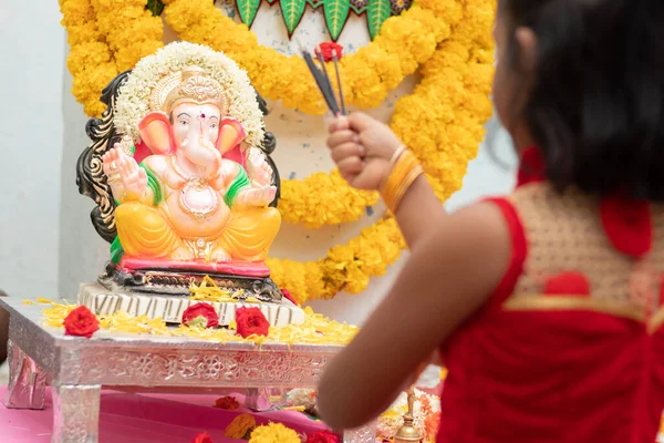 Niño rezando cerrando los ojos frente al ídolo de dios Ganesha sosteniendo u ofreciendo incienso en la mano durante la celebración del festival de ganapati en casa. —  Fotos de Stock