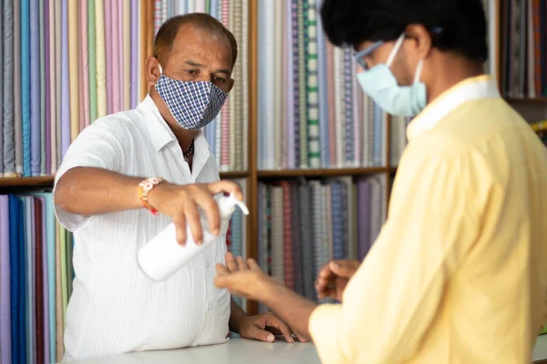 Shopkeeper dar desinfectante de manos al cliente para dejar de propagar coronavirus o infección covid-19 - concepto de seguridad, medidas de higiene en el negocio y el lugar de trabajo. —  Fotos de Stock