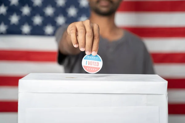Koncept af USA valg, Close up af hænder Sætte jeg stemte klistermærke inde Afstemning boks med amerikansk flag som baggrund. - Stock-foto
