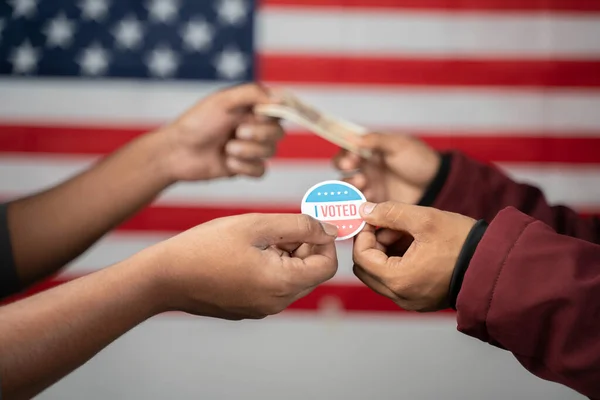 Концепція купівлі голосів на американських виборах, що проявила обміном я проголосував наклейкою з грошима на прапор США як тло. — стокове фото