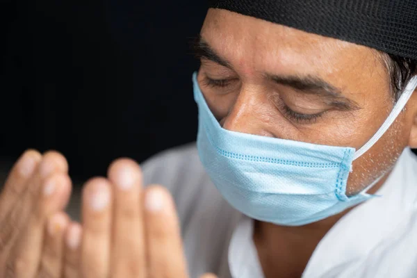 Vista de ángulo alto de cerca plano del hombre musulmán en máscara médica preformando Salah o la oración por los ojos cerrados. — Foto de Stock