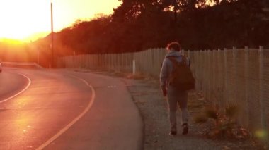 Yolda yürüyen bir adam. Gün batımı ve arabalar