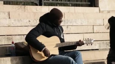 Bilinmeyen müzisyen gitar çalıyor ve sokakta şarkı söylüyor.