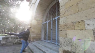 Tarihi kemer binasında yürüyen genç adam. Tarihi yerleri ziyaret ediyorum. Adam gölgeli eski kemer binasına gidiyor. Erkek turist
