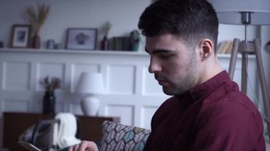 Ciddi adam yakından ev sohbet online Internet bağlantısı genç portre mobil teknoloji iletişim kanepede bir tablet sit kullanır yakışıklı yalnız ağır çekim 