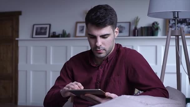 남자는 태블릿을 사용합니다 태블릿 그리고 집에서 소파에 손으로 메시지를 슬로우 — 비디오
