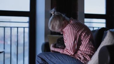 Genç ve güzel bir kadın kanepede köpeğini öpüyor, Şirin Paspaslar siyah kanepede oturan bir kızı, köpeği ve sahibini öpüyor.