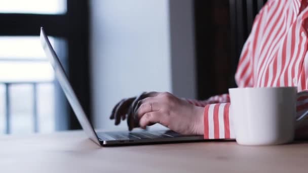 一个女人在笔记本电脑上写字 桌上有一杯咖啡的特写镜头 — 图库视频影像