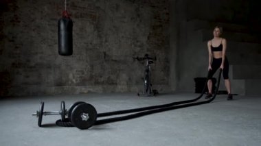 Genç Yetişkin kız savaş ip egzersiz sırasında çapraz pratik egzersiz spor salonunda uygun.