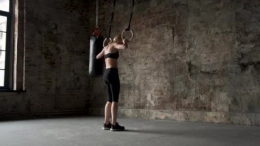 Jimnastik halkaları üzerinde germe yapıyor genç fit kadın. Spor salonunda halkalarla egzersiz kas genç kadın atlet. Jimnastik halkaları üzerinde pull-up yapıyor genç fit kadın