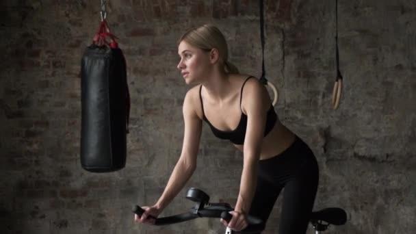 ジムで自転車に乗るフィットネス女性のクローズアップ 運動用自転車の女性 ジムバイクで激しいトレーニングをしている女の子 — ストック動画