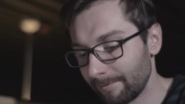 Ofisinde oturmuş bilgisayar üzerinde çalışan ve gözlük takan sakallı bir gencin portresi. Bilgisayar ekranı gözlüklerine yansıyor. Kızıl Sinema Kamerası 'nda 4K (UHD).