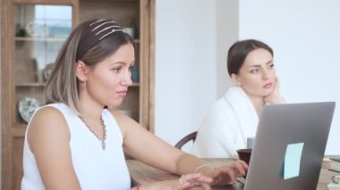 Kadınlar evde bilgisayar ve tabletle çalışıyorlar. Üç kız arkadaş evde oturup iş yapıyor.. 