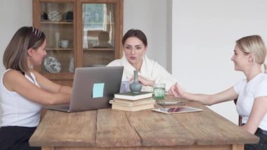 Evdeki üç güzel kadın kanepede oturmuş bilgisayar kullanıyor ve gülümsüyor. İçeride, millet..