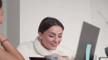 Esmer olan arkadaşıyla konuşuyor ve gülümsüyor. Güzel, güler yüzlü, kendine güvenen genç bir kadın. Güzel bir yüz. Mutlu bir milenyum kızı.