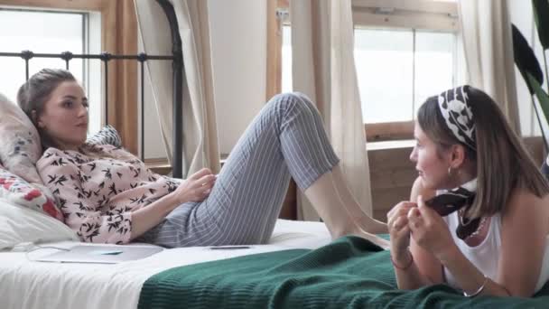 二人の十代の女の子が家でベッドに横になって幸せ 女性はリラックス ライフスタイル 若者と喜びの概念 — ストック動画