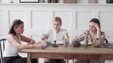 Evde sohbet eden üç kadın mutfağın ortasında modern masanın yanında duruyor. Son sınıftaki hanımlar şarap içip yemek yiyorlar. 