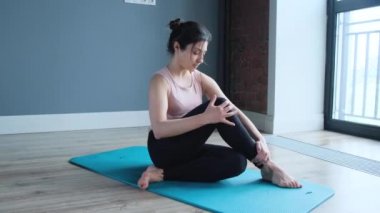 Spor kıyafetlerinde mavi bir paspasın üzerinde farklı asanas performansları sergileyen genç kadın..