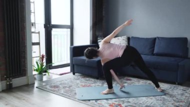 Yogi kızı Sarvangasana pozu veriyor. Rahatlamak için kalp kasları omurga için iyileşiyor. Sonra Namaste ile nilüfer çiçeğine dönüşüyor. Eğitim, evde yoga, oturma odasında.