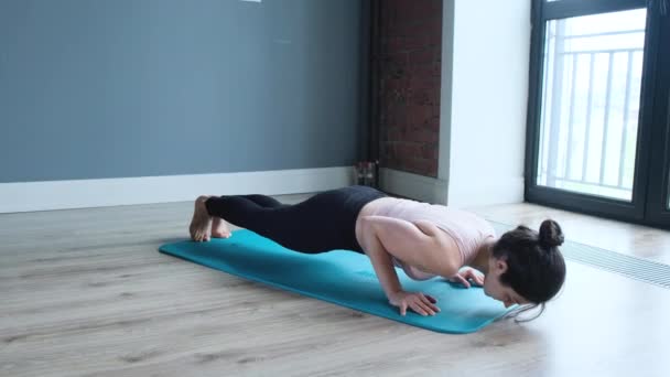 年轻女子在家练习瑜伽 在家里一个年轻的女运动员在蓝色垫子上做瑜伽姿势时被射中 — 图库视频影像