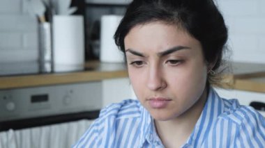 Mavi çizgili tişörtlü, evde bilgisayarla çalışan parlak bir mutfakta oturan Hintli genç bir kızın fotoğrafını çek.