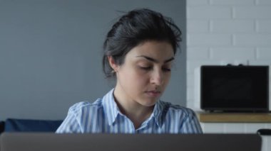 İnternette çalışan ve not defterine notlar alan Hintli ciddi bir kadına yakın çekim.