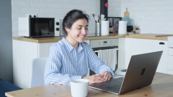一位快乐的印度年轻女人在她坐在家里的电脑上与朋友们一起微笑和在线交流 — 图库视频影像