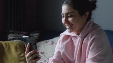 Neşeli Genç Hintli Kadın akıllı telefon tutuyor ve internetten video görüşmesi yapıyor. 
