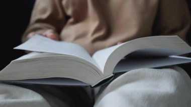 Kitap okuyan ve sayfayı çeviren genç bir Hintli kadının yakın çekimi.