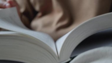 Genç bir Hintli kadın kitap okuyor ve sayfayı çeviriyor.