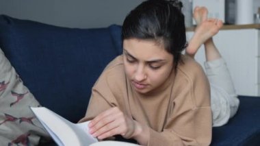 Yatakta kitap okuyan genç bir Hintli kadının yakın plan fotoğrafı.