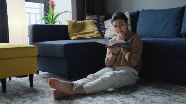 Young Indian Woman Sitting Next Sofa Thoughtfully Reading Book Turning — Stock Video