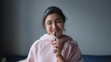 Mutlu Hintli kadın evde şarkı söylüyor başarılı yaşam tarzını kutluyor dans ediyor karaoke müzik eğlencesinin tadını çıkarıyor